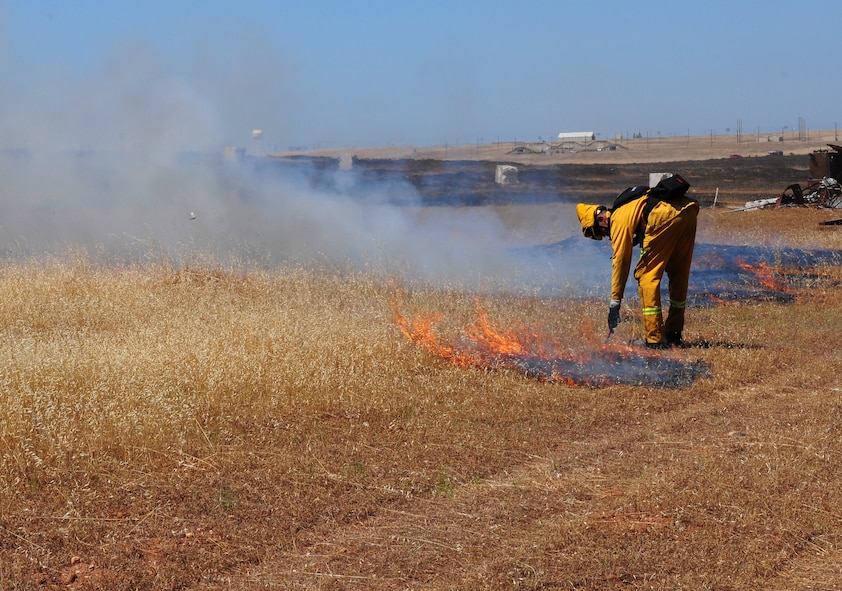 Airman 1st Class Sean Russell, 9th Civil Engineering Squadron firefighter, uses a flare to burn the remaining unburned patches of grassland during the prescribed burn of the M60 machine gun range at Beale Air Force Base, Calif., June 19, 2012. Team Beale firefighters often support local fire departments during the fire season. (U.S. Air Force photo by Senior Airman Allen Pollard/Released)