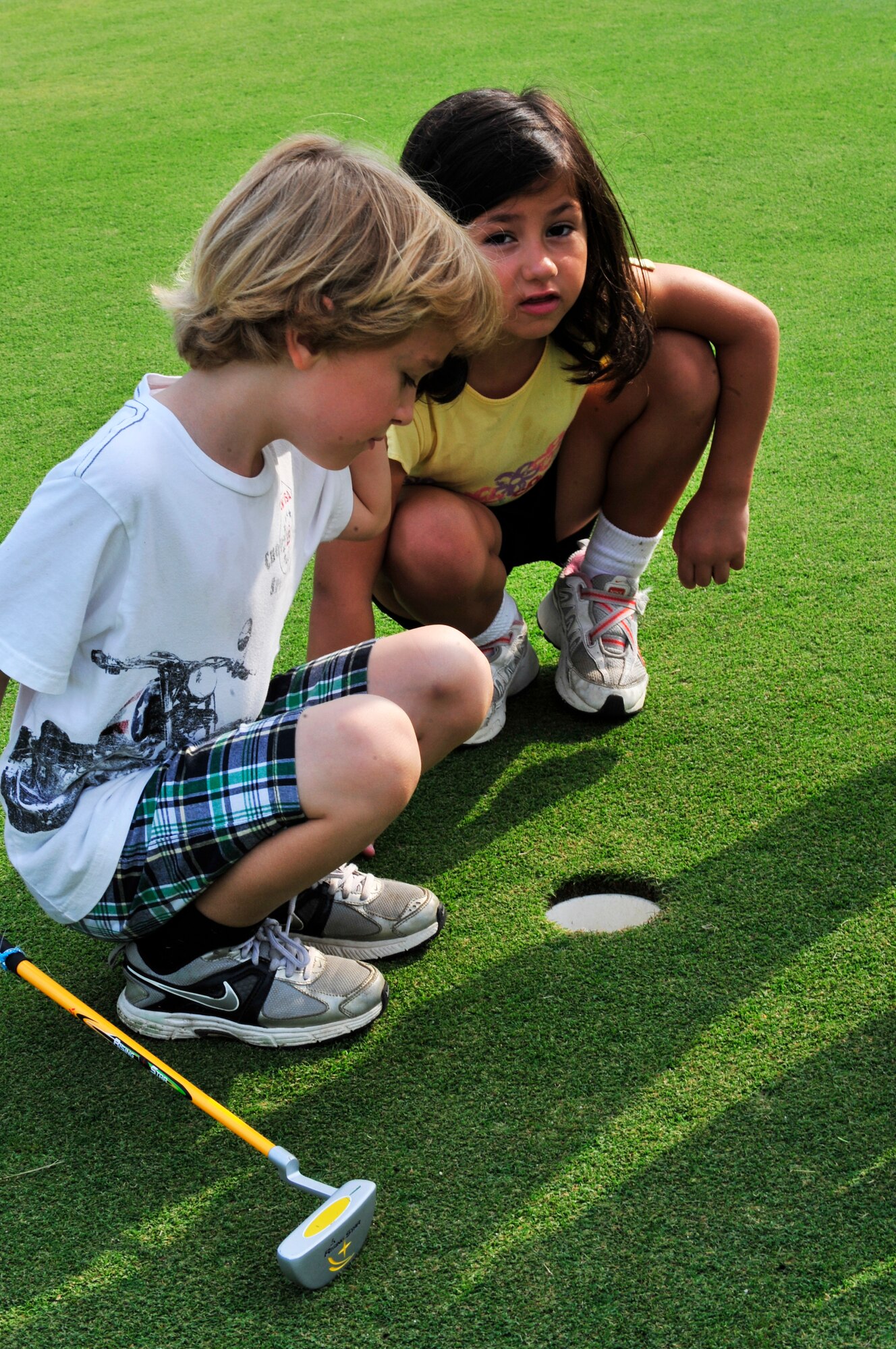 Jackson Murray (left) and Karyna Gonzalez (right) look for a bug in a hole at the Carolina Lakes Golf Course, Shaw Air Force Base, S.C., June 20, 2012.  Both Murray and Gonzalez attended the four-day Air Combat Command kids’ golf class which was organized by Katharine Williams, Carolina Lakes director of golf and former Professional Golf Association professional.(U.S. Air Force Airman Nicole Sikorski/Released)
