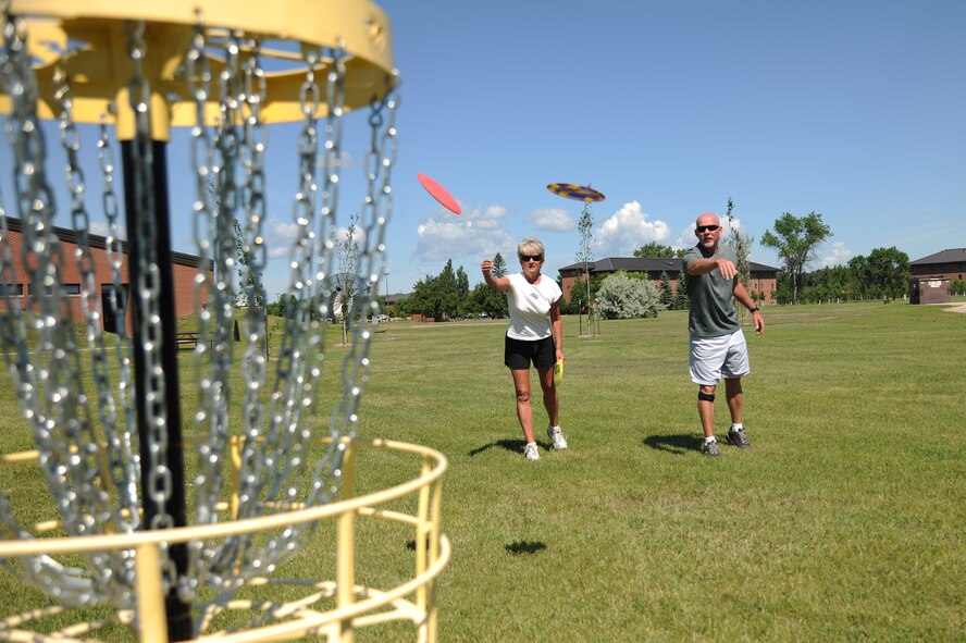 Retired Air Force couple Patricia and Johnny Broshear toss discs into a goal June 22, 2012, on Grand Forks Air Force Base, N.D. The Broshears helped clean up and maintain the Grand Forks AFB disc golf course this summer. (U.S. Air Force photo/Airman 1st Class Derek VanHorn)