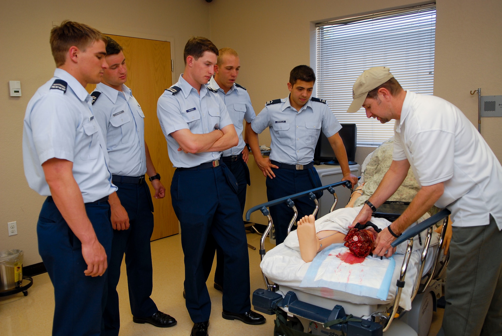 Roger Cowart, 56th Medical Support Squadron medical simulation specialist, shows U.S. Air Force Academy cadets how to properly apply a tourniquet to a patient using a simulator dummy June 11 at Luke Air Force Base, Ariz. The cadets visited Luke's education and training building as part of the Academy's Operation Air Force program that allows cadets to visit military installations to get a better understanding of officer careers. (U.S. Air Force photo by Airman 1st Class Grace Lee)
