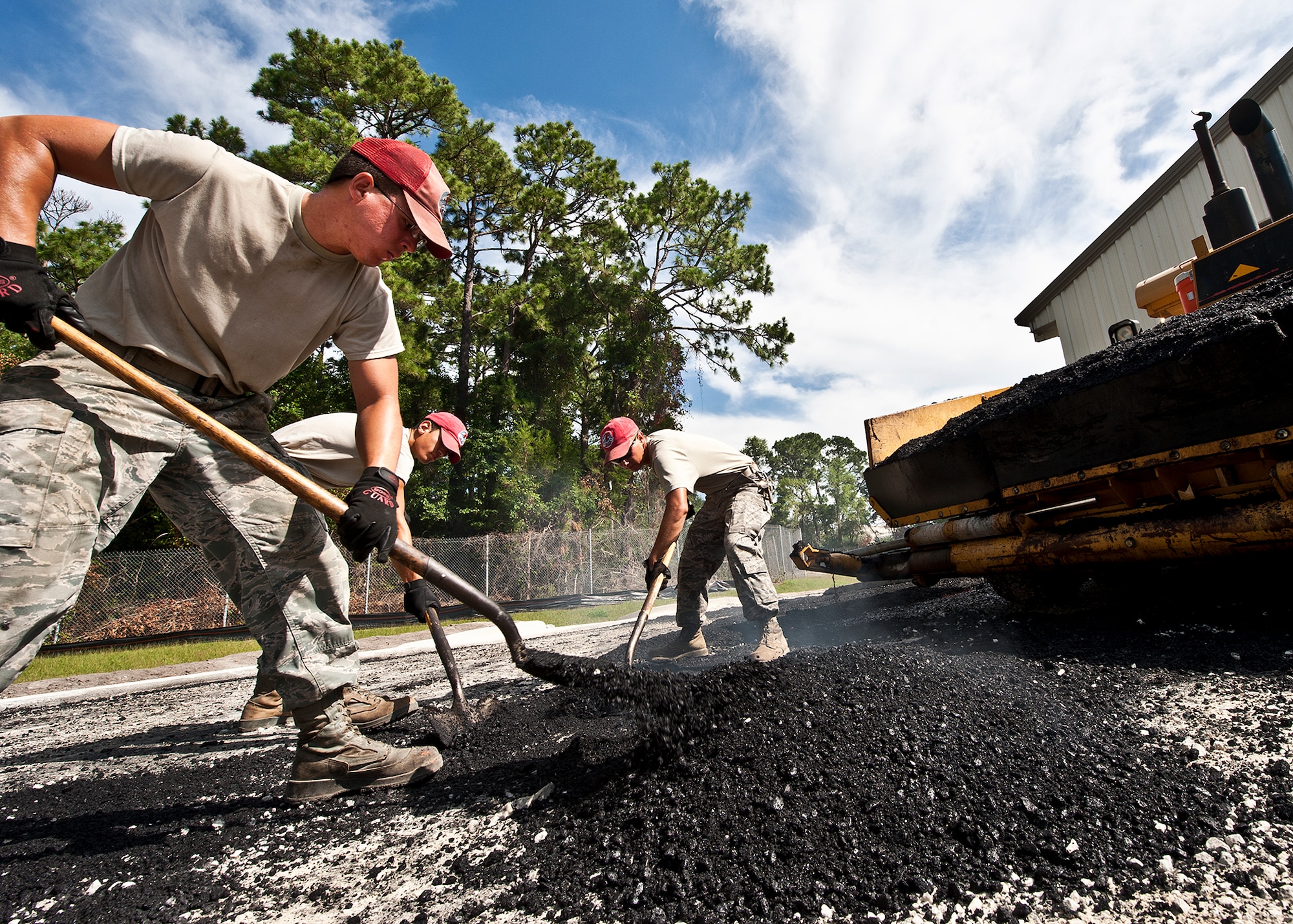 The Red Hats of the 823rd Red Horse Squadron scoop up asphalt at the Combat Shield compound at Eglin Air Force Base, Fla., June 20.  The two-month paving project by the Hulburt Field Airmen changed the layout of the roads in and out of the compound to allow for large haulers to maneuver and exit with ease.  (U.S. Air Force photo/Samuel King Jr.)