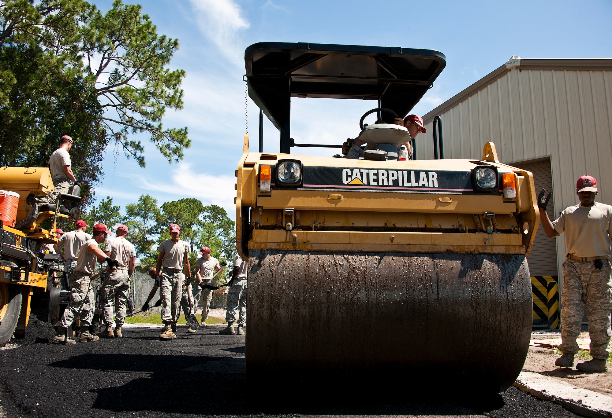 The Red Hats of the 823rd Red Horse Squadron spread out the newly poured asphalt at the Combat Shield compound at Eglin Air Force Base, Fla., June 20.  The two-month paving project by the Hulburt Field Airmen changed the layout of the roads in and out of the compound to allow for large haulers to maneuver and exit with ease.  (U.S. Air Force photo/Samuel King Jr.)