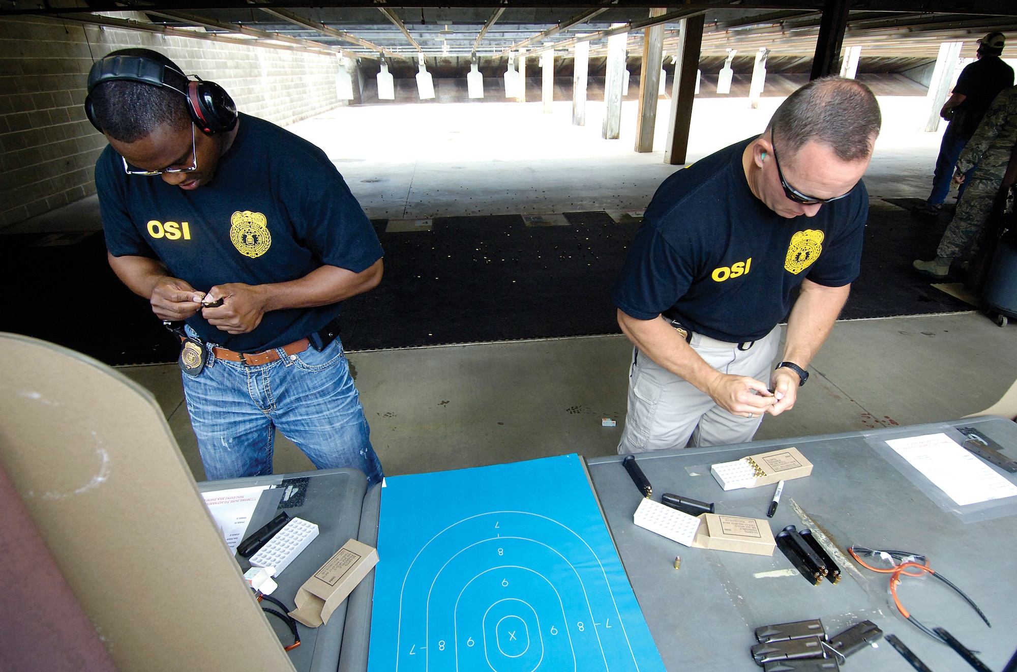 Air Force Office of Special Investigations Detachment 114 shooting team members Special Agent Reginald Robinson, left, and Det. 114 commander Maj. Jeff Johnson, reload at the Tinker Combat Arms range during their annual Pistol Competition time on the line June 15. (Air Force photo by Margo Wright)