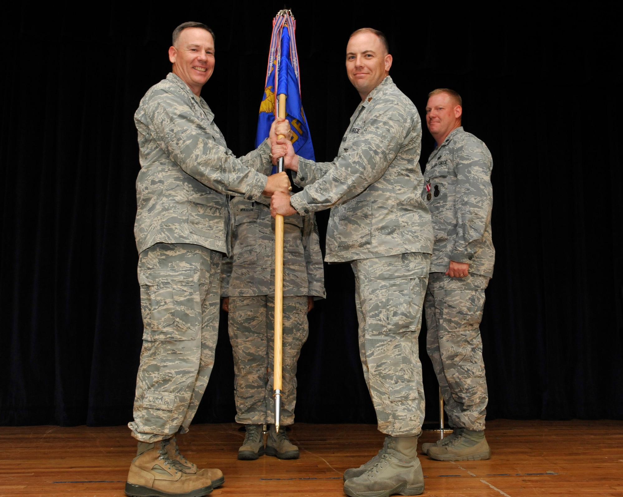 U.S. Air Force Maj. Christopher M. Sheffield, 20th Security Forces Squadron incoming commander, takes the flag from Col. Walter J. Fulda, 20th Mission Support Group commander, while Lt. Col. Mark R. Walsh, 20th Security Forces Squadron outgoing commander, watches them during the 20th SFS change of command ceremony at the Community Activity Center, Shaw Air Force Base, S.C., June 22, 2012. Sheffield replaced Walsh and will be responsible for protecting the United States’ largest F-16 fighter wing while presiding over 250 security forces members. (U.S. Air Force photo by Senior Airman Amber E. N. Jacobs/Released)