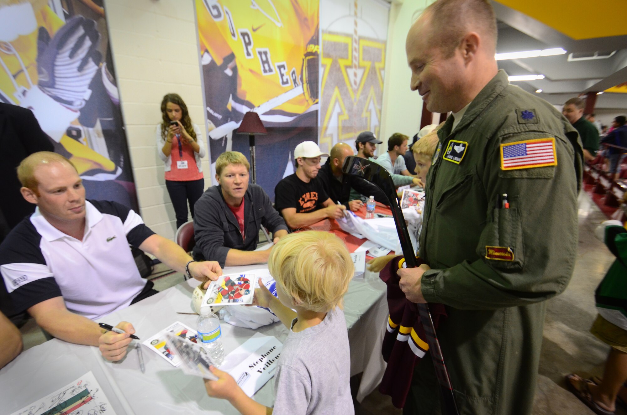 Lt. Col. Jamie Lindman, 133rd Airlift Wing pilot, and his 6-year-old son Bennett get autographs from National Hockey League hockey players. Defending the Blue Line hosted a charity game and autograph session at the Ridder Arena in Minneapolis on June 20. DTBL is a non-profit organization created by Army National Guard Soldiers to military families with costs associated with youth hockey. They provide financial assistance for registration fees, free equipment, summer hockey camps, and to send families to the Xcel Energy Center to Minnesota Wild games, as well as other NHL venues. (U.S. Air Force photo by Tech. Sgt. Bob Sommer)