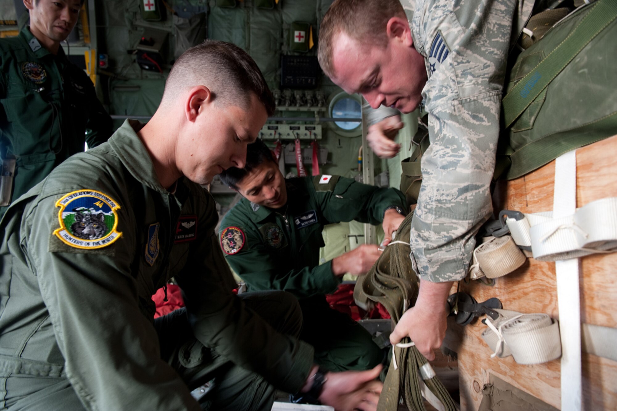 U.S. Air Force Staff Sgt. Mark Manning, front left, and TSgt Michael Dunkelberger, front right, examine the air drop system with members of the Japanese Air Self Defense Force during pre-flight inspections for the Japanese C-130 Hercules during Red Flag - Alaska on the flight line of Joint Base Elmendorf-Richardson, Alaska June 19. The C-130 Hercules offers a maximum speed of 600 kilometers an hour with a payload of 19,400 pounds and can be used for air drops. Red-Flag Alaska is designed to strengthen bilateral ties between nations and offers the JASDF the opportunity to improve aerial tactics. (U.S. Air Force photo/Staff Sgt. Robert Barnett)