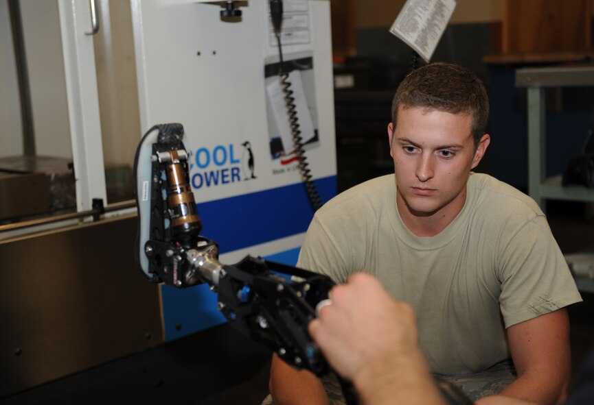 Senior Airman Nathaniel Danner, 2nd Maintenance Squadron metals technology shop, looks at the prosthetic leg of Mike Schultz, a MotoX dirt bike and SnoX snowmobile racer who lost his left leg after an accident, on Barksdale Air Force Base, La., June 20. The American300 tour returned here as part of the "Do Something Amazing Outdoors" summer challenge to speak with Airmen from various shops and base organizations. (U.S. Air Force photo/Airman 1st Class Benjamin Gonsier)(RELEASED)