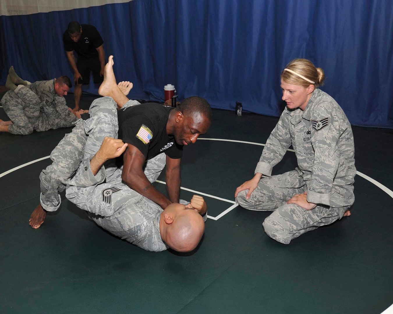 Air Force Staff Sgt. Jesse Armstrong, a security forces technical training instructor with the 343rd Training Squadron, looks on as Army Sgt. 1st Class Jesse Thorton, NCO in charge of the Army III Corps combatives program at Fort Hood, Texas, demonstrates the cross collar choke on Air Force Staff Sgt. Mark Velasquez, technical training instructor with the 343rd TRS, June 12 at the Warhawk Fitness Center. (U.S. Air Force photo/Alan Boedeker)