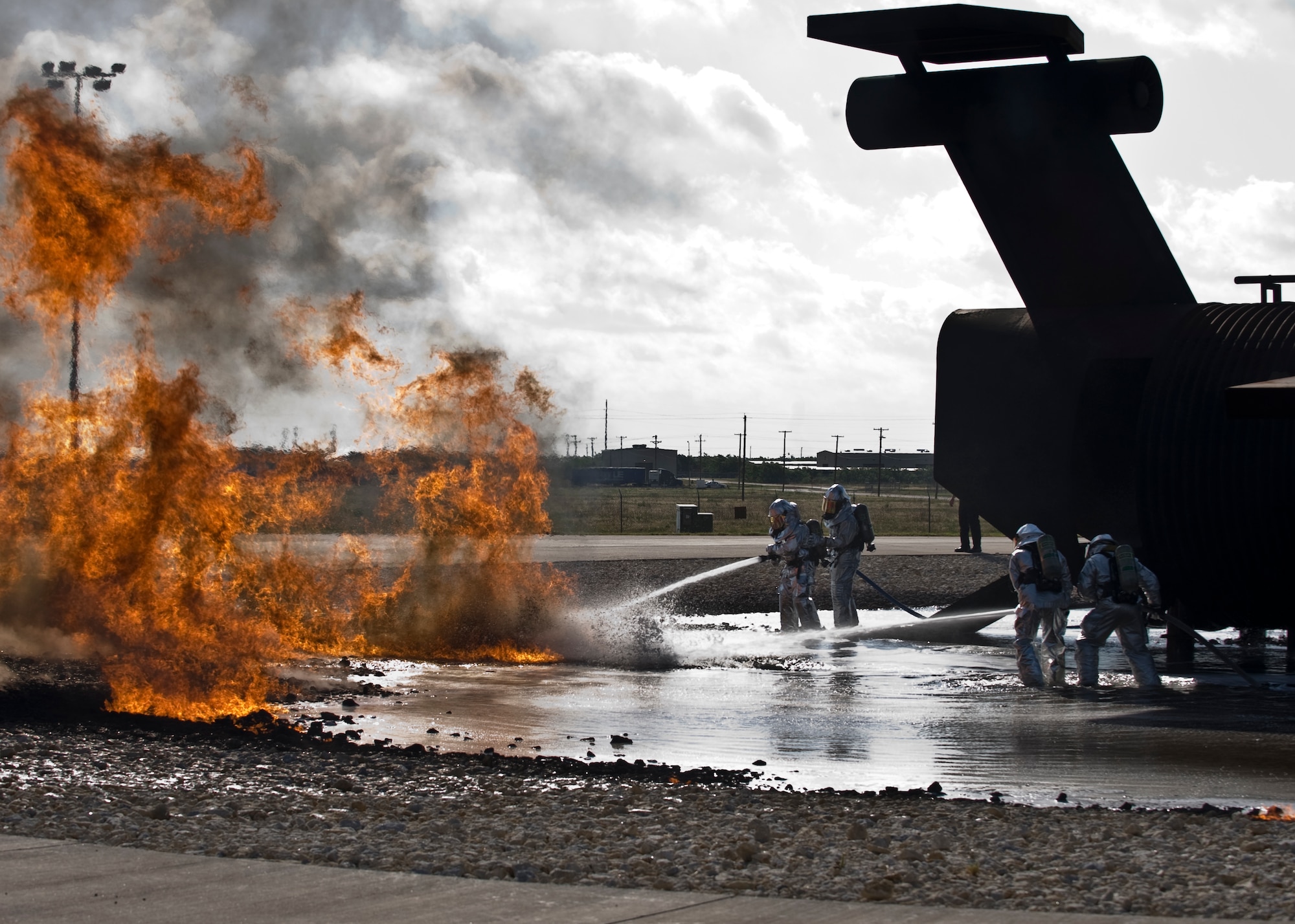 U.S. Air Force Col. David Béen, 7th Bomb Wing commander, and Chief Master Sgt. Kenneth Lindsey, 7th Bomb Wing command chief, and two Dyess firefighters extinguish a fire June 20, 2012, at the Fire Department training grounds on Dyess Air Force Base, Texas. Base leadership experienced firefighting from a firefighters point of view. Training started with an exterior Jet Propellant 8 explosion, followed by an interior propane explosion in the cockpit to demonstrate the difference between the two fuel types. Firefighters are responsible for protecting Air Force assets in case of fire. Dyess’ Fire Department training grounds enable airmen to qualify on both propane and jet fuel. (U.S. Air Force photo by Airman 1st Class Peter Thompson/ Released)
