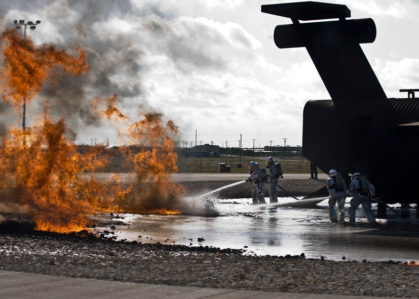U.S. Air Force Col. David Béen, 7th Bomb Wing commander, and Chief Master Sgt. Kenneth Lindsey, 7th Bomb Wing command chief, and two Dyess firefighters extinguish a fire June 20, 2012, at the Fire Department training grounds on Dyess Air Force Base, Texas. Base leadership experienced firefighting from a firefighters point of view. Training started with an exterior Jet Propellant 8 explosion, followed by an interior propane explosion in the cockpit to demonstrate the difference between the two fuel types. Firefighters are responsible for protecting Air Force assets in case of fire. Dyess’ Fire Department training grounds enable airmen to qualify on both propane and jet fuel. (U.S. Air Force photo by Airman 1st Class Peter Thompson/ Released)