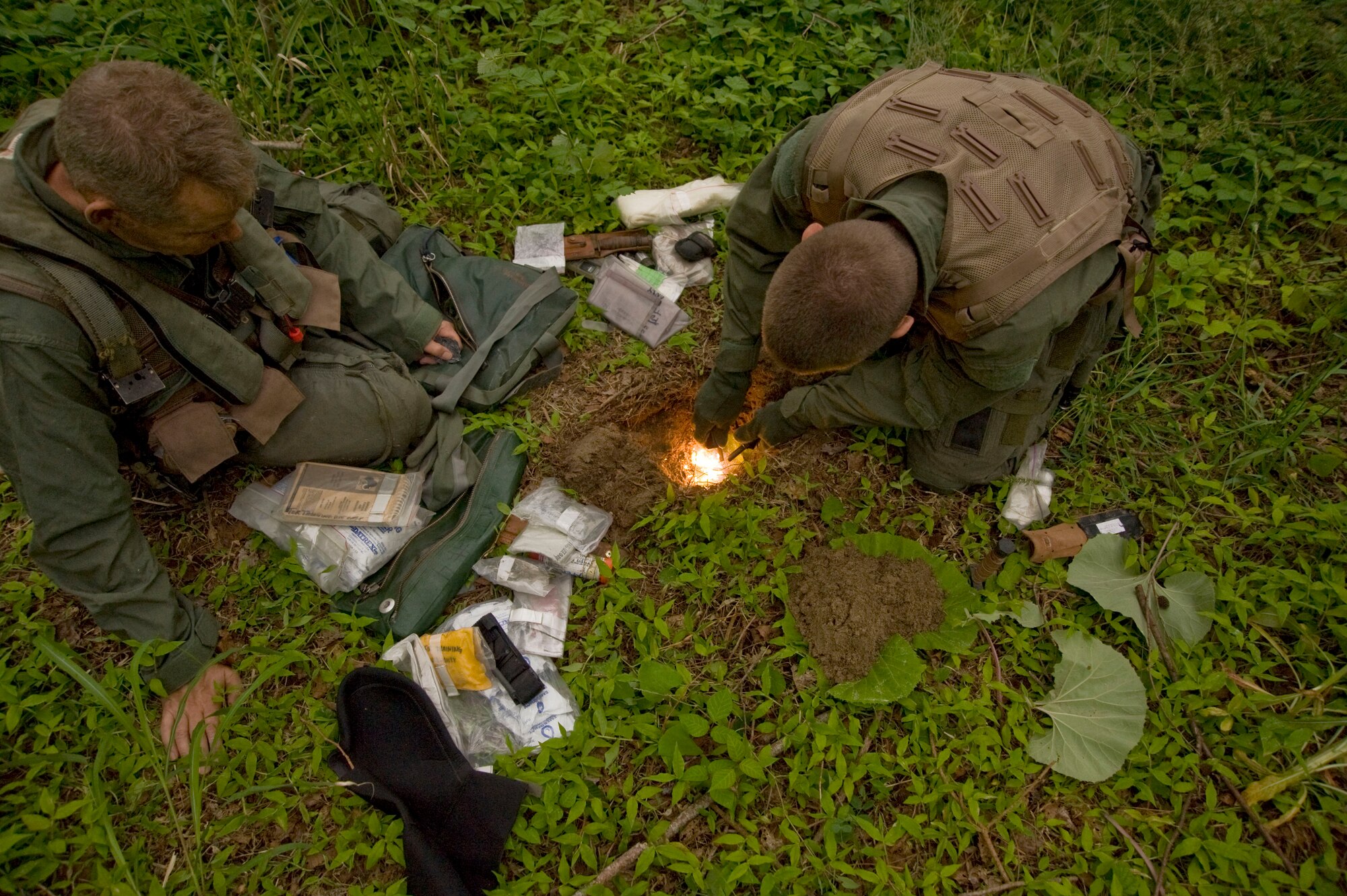 U.S. Air Force Chief Master Sgt. James Laurent, left, 35th Fighter Wing command chief, watches as Senior Airman Michael Dixon, 35th Operations Support Squadron survival, evasion, resistance and escape specialist, demonstrates how to make a fire during SERE training at Draughon Range, Japan, June 20, 2012. Along with teaching how to conceal a fire, Dixon spent the day and part of the night explaining how to navigate, hide, find food and survive if isolated. (U.S. Air Force photo by Staff Sgt. Nathan Lipscomb/Released)