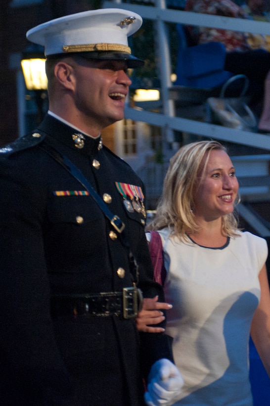 Capt. John Mclaughlin, ceremonial hoster, escorts a woman to her seat before the start of a Friday Evening Parade at Marine Barracks Washington June 22.