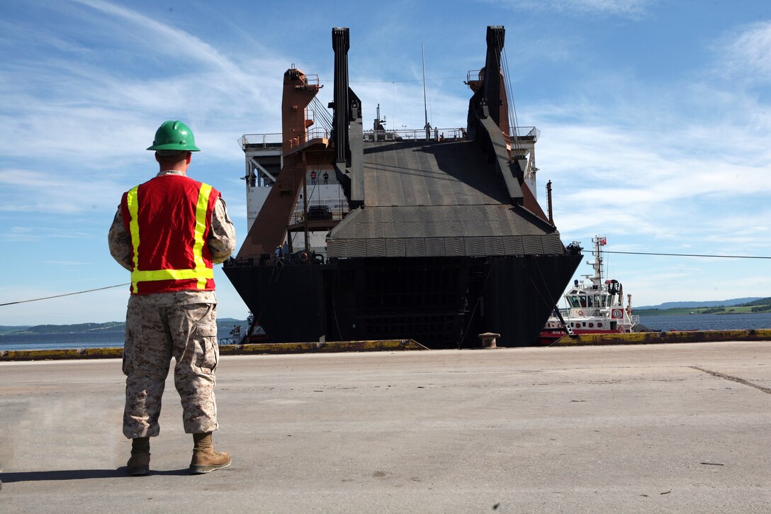 Sergeant William Kruger an embark specialist assigned to Blount Island Command watches the ramp lower on the USNS Sgt Mate Kocak during an off-load/cross-leveling operation to retrograde equipment into the caves, belonging to the Marine Corps Prepositioning Program-Norway.  During this operation more than 150 vehicles and 200 shipping containers were transferred on or off the Kocak and staged for transportation to the caves or loaded back onto the ship. The MCPP-N facility is comprised of eight locations totaling more than 900,000 square feet of storage space. Inside the caves is  471,445 sq. ft. of climate controlled storage space, regulated to between 45 to 55 percent humidity and a regulated temperature of between 45 to 50 degrees. This precise regulation allow for tents, vehicle tires and parts and other climate sensitive equipment to be stored safely, and maintain a high level of accessibility to be readily deployable for any contingency that may arise.