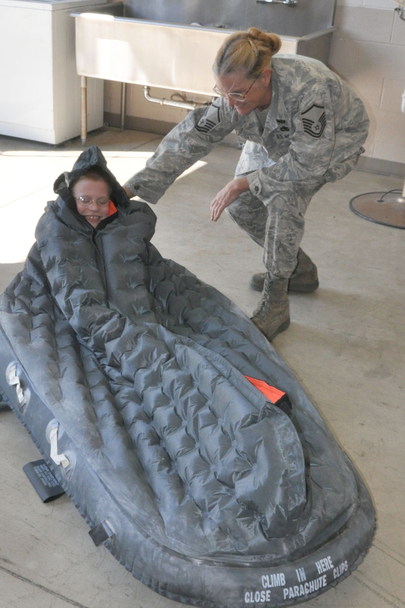 YOUNGSTOWN AIR RESERVE STATION, Ohio -- Air Force Reserve Master Sgt. Cindy Cox, a life support equipment craftsman with the 910th Airlift Wing helps 10-year-old Hunter Crites of Austintown, Ohio fit snugly inside a floatation device as part of a tour here June 22. Hunter was selected by Akron Children's Hospital Mahoning Valley to be honored as a pilot for a day. He is being treated for Cerebral Palsy. Hunter was sworn in as an honorary second lieutenant, taxied aboard a C-130 Hercules aircraft and given a special tour of the installation. The 910th Airlift Wing pilot for a day program began in 2000 to help bring a ray of sunshine into the lives of children being treated for chronic or life threatening conditions.
