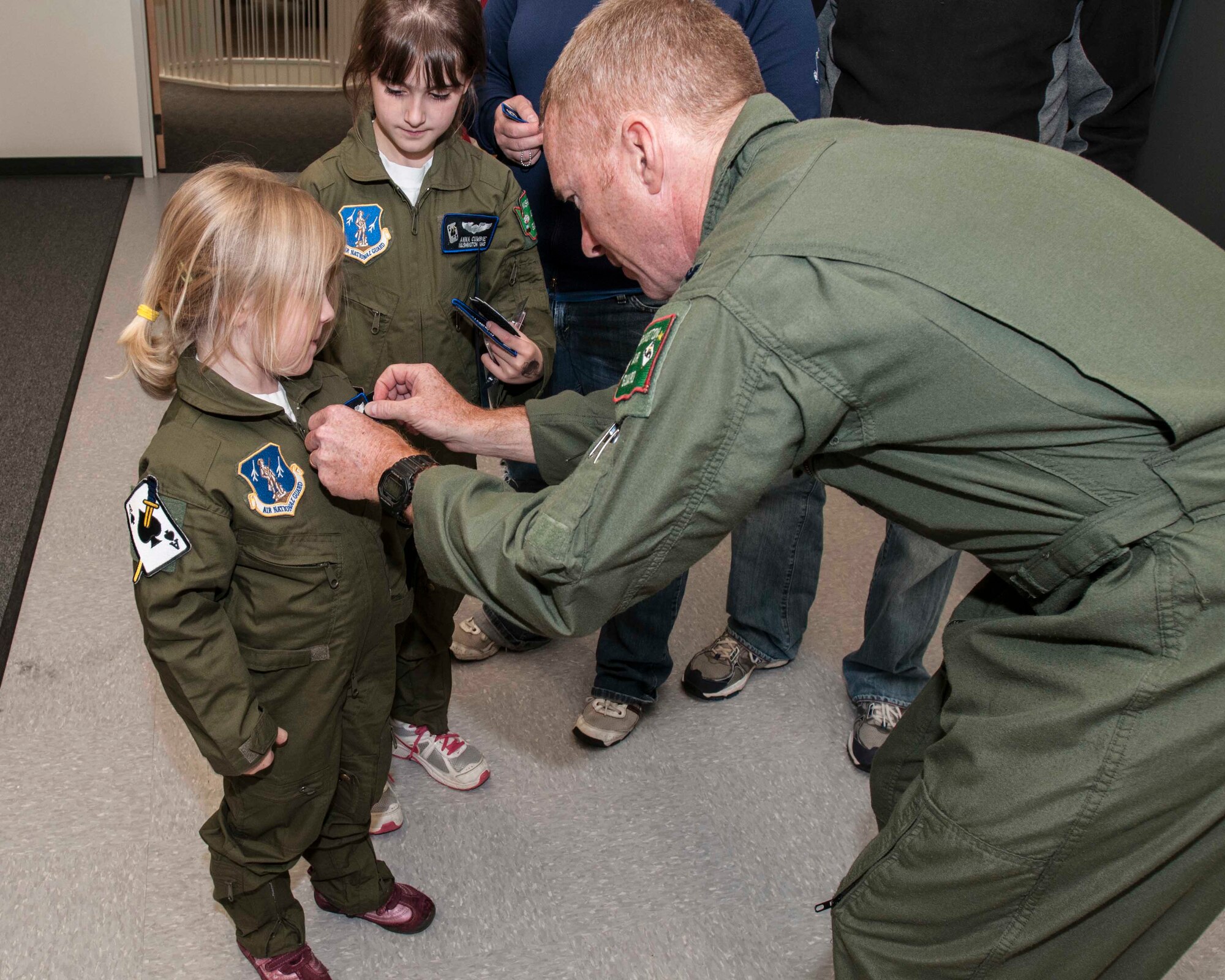 Col. Richard Kelly, 141st Air Refueling Wing Commander, places pilot’s wings on Madeline Cumbie as her sister Anna looks on during the Pilot for a Day graduation ceremony.  The two sisters were selected to participate in the wing’s honorary pilot training program May 30, 2012 at Fairchild AFB in Spokane, WA. (U.S. Air Force photo by Master Sgt. Michael Stewart/Released)