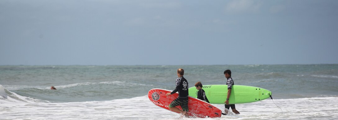 Two Indo Jax surf instructors head into the water at Onslow Beach aboard Marine Corps Base Camp Lejeune, June 15. Indo Jax holds summer camps for youth as well as group classes and individual classes for adults.