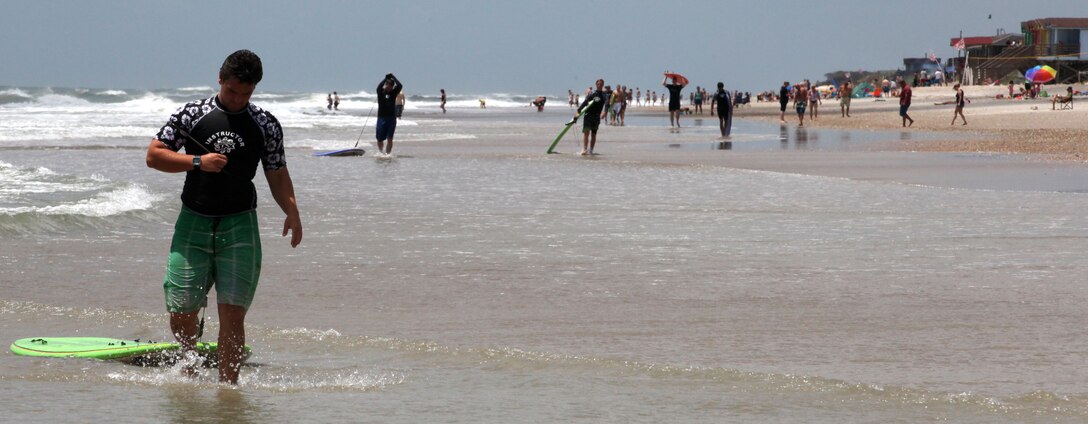 A Indo Jax surf instructor leads a group of Wa Lu Warriors further along the shore while out surfing at Onslow Beach aboard Marine Corps Base Camp Lejeune, June 15. Indo Jax provides many classes for free to members of the military community and typically has sliding prices for their other classes based on rank. 