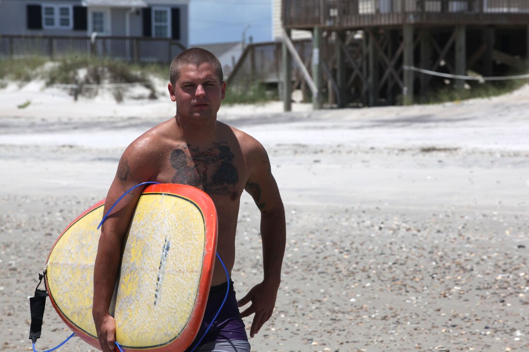 Cpl. Chase Dale heads back into the water after surfing through the waves at Onslow Beach aboard Marine Corps Base Camp Lejeune, June 15. Dale is a surfing enthusiast who has surfed since his youth, he beleives that surfing offers a great workout to the military cummunity. 