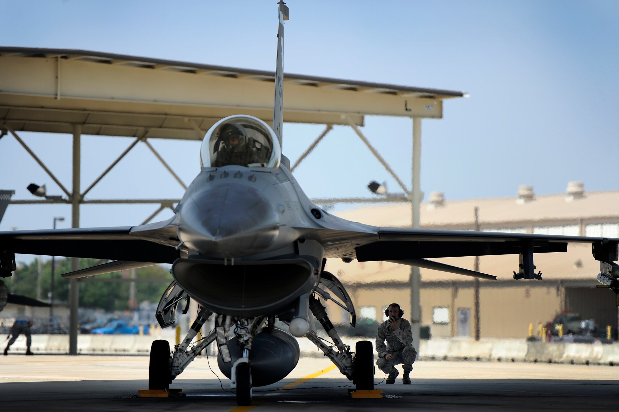 U.S. Air Force Airman 1st Class Brian Fisher, 20th Aircraft Maintenance Squadron crew chief, communicates with the pilot of an F-16 Fighting Falcon as he performs his final check on the aircraft before launching it, June 19, 2012, Shaw Air Force Base, S.C. Crew chiefs assigned to the 20th AMXS work around the clock maintaining and launching F-16’s for three fighter squadrons assigned to the 20th Fighter Wing. (U.S. Air Force photo by Senior Airman Kenny Holston/Released)