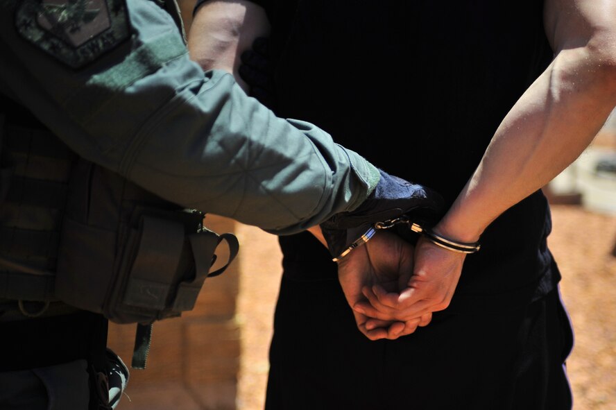 Members of the Clovis, N.M., Police Department's Special Weapons and Tactics team handcuff U.S. Air Force Senior Airman Daniel Santiago, 27th Special Operations Security Forces Squadron investigator, during a hostile threat exercise at Cannon Air Force Base, N.M., June 20, 2012. Air Commandos joined forces with the Clovis Police Department to diffuse the scenario.(U.S. Air Force photo by Airman 1st Class Eboni Reece)