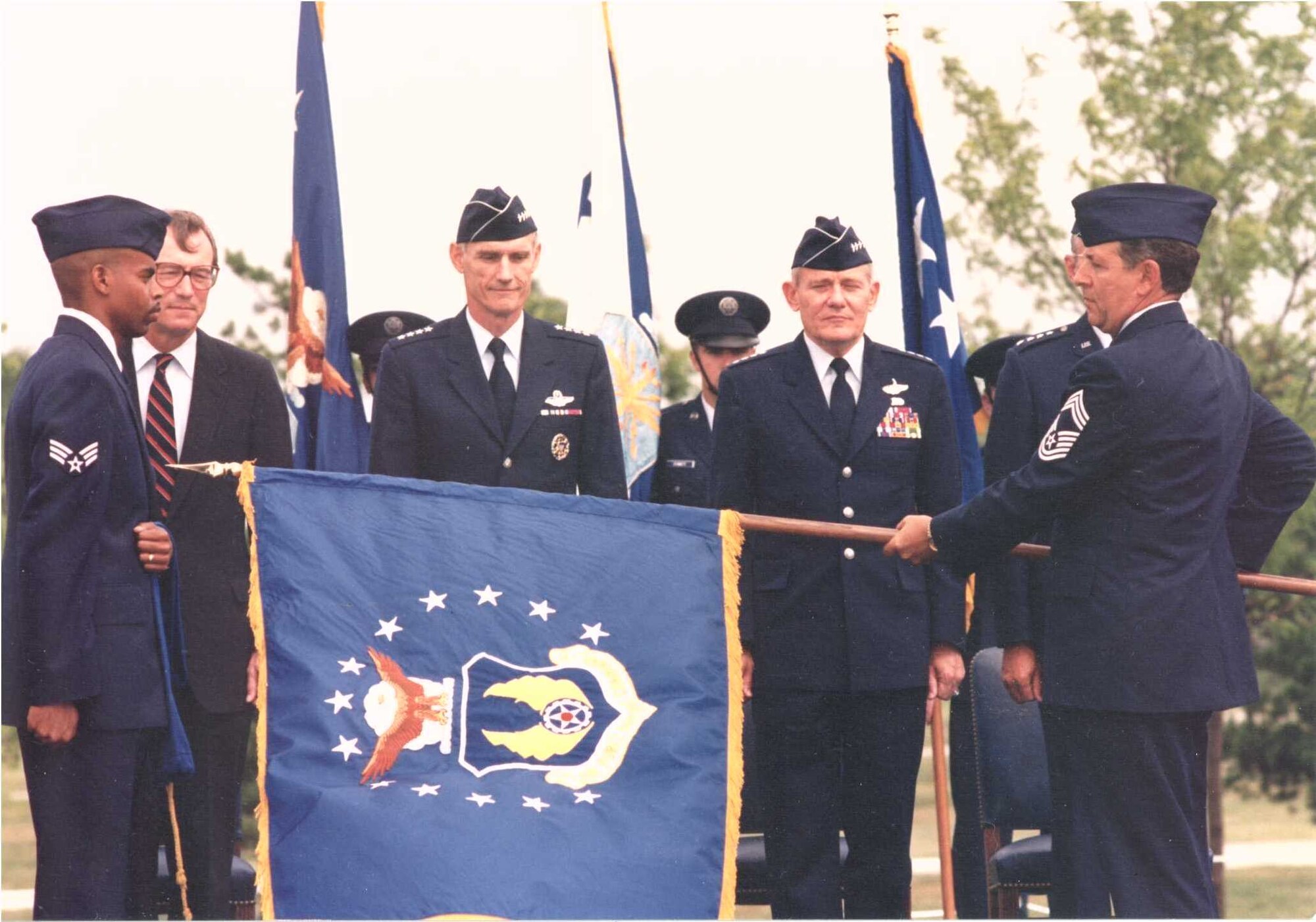 Secretary of the Air Force Dr. Donald B. Rice (from center left), Air Force Chief of Staff Gen. Merrill A. McPeak and Air Force Materiel Command Commander Gen. Ronald W. Yates stand as the AFMC flag is unfurled at the command's activation ceremony July 1, 1992. This year AFMC celebrates its 20th anniversary of providing expeditionary capabilities to the warfighter through development and transition of technology, acquisition management, test and evaluation, and sustainment of all Air Force weapon systems.  (File photo)