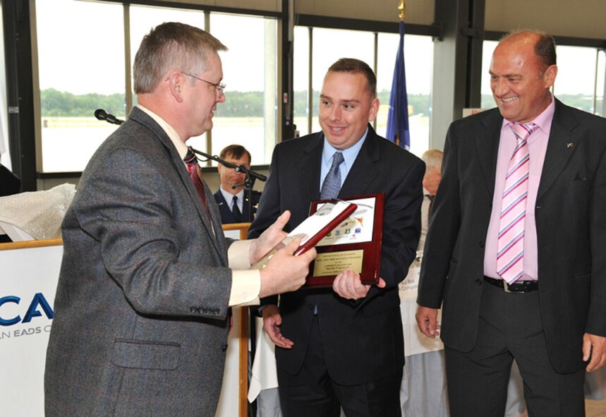 MANCHING, Germany - Chris Lind (center), Electronic Systems Center’s NATO E-3A Large Aircraft Infra-Red Counter Measures program manager, and Thomas Merkl (right), Cassidian team leader, receive commemorative plaques from Pete Maske, Northrop Grumman program manager, June 5 at a ceremony to commemorate the completion of the LAIRCM Retrofit Program. (Photo by Andrea Hohenforst)