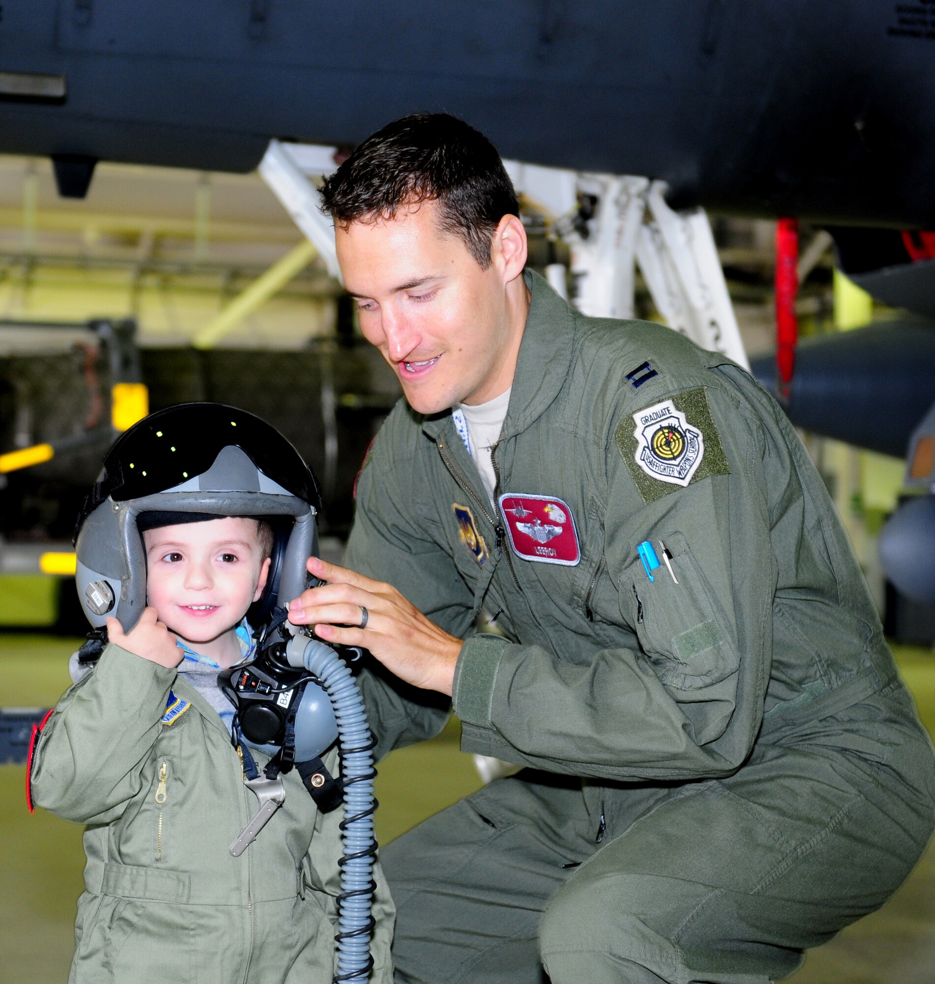 ROYAL AIR FORCE LAKENHEATH, England – Capt. Benjamin Donberg (right), 492nd Fighter Squadron pilot, fits Callum Carr, 4-year-old, during a Pilot for A Day tour June 22, 2012. Carr was diagnosed with Ewings carcinoma and has been undergoing treatment for several months. The Pilot for a Day program is new to RAF Lakenheath and provides children in the local community who are fighting life-threatening illnesses or conditions a day of learning and fun as a break from doctor visits. (U.S. Air Force photo by Airman 1st Class Cory D. Payne)