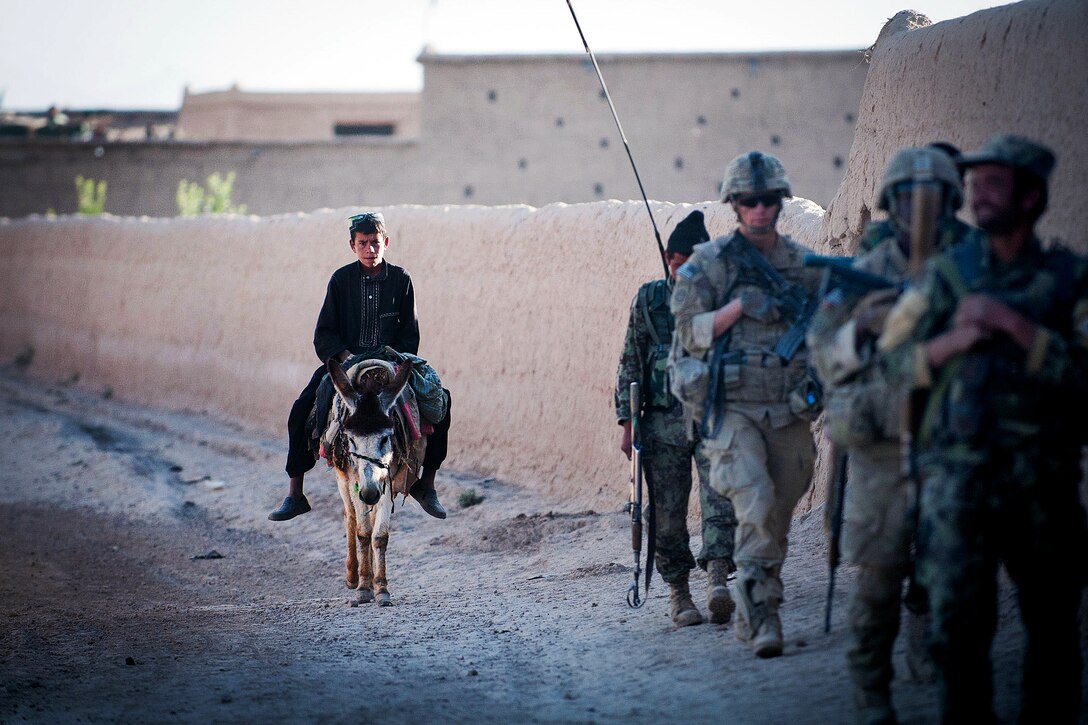 An Afghan boy rides a donkey as U.S. paratroopers and Afghan soldiers ...