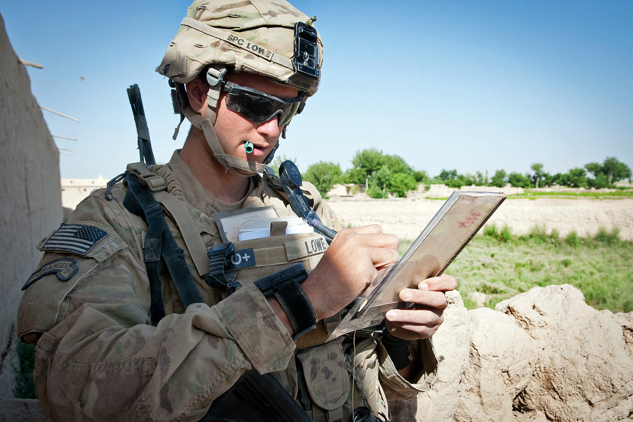U.S. Army Spc. Jesse Lowe marks coordinates on a map during a partnered
