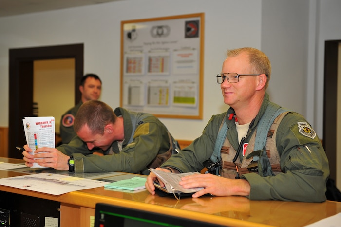 SPANGDAHLEM AIR BASE, Germany – Brig. Gen. Chris Weggeman, right, 52nd Fighter Wing commander, goes through a briefing to gather weather and flight information at the 480th Fighter Squadron operations desk here June 21 before his final F-16 Fighting Falcon launch. Weggeman commanded the 52nd FW for two years. (U.S. Air Force photo by Airman 1st Class Dillon Davis/Released)