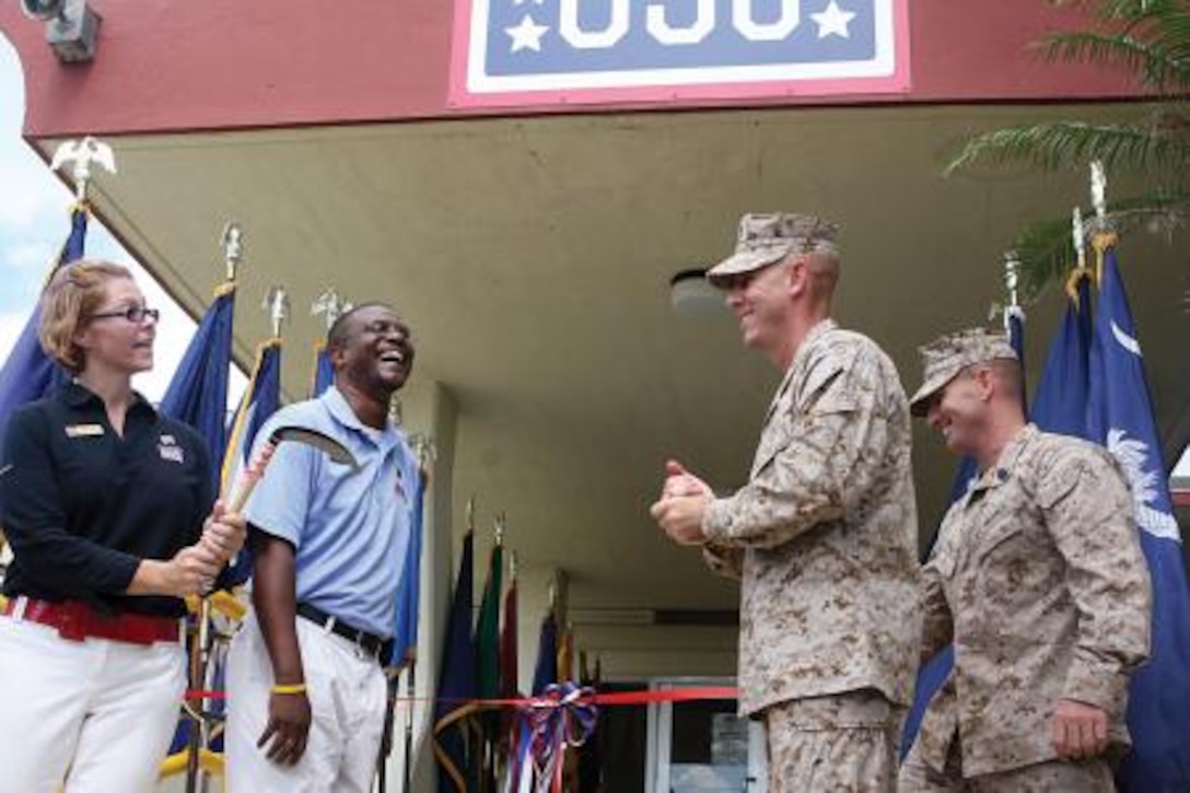 Col. James G. Flynn, center right, commanding officer of Marine Corps Air Station Futenma, Sgt. Maj. Brent L. Cook, far right, sergeant major of MCAS Futenma, and Freddie Cotton, center, manager of USO Futenma, chuckle when Robin Miller, far left, country director of USO Okinawa, pulls out a kama instead of ceremonial scissors to cut the ribbon signifying the reopening of USO Futenma on MCAS Futenma Oct. 28. The kama is a traditional Okinawan farming tool still in use today.