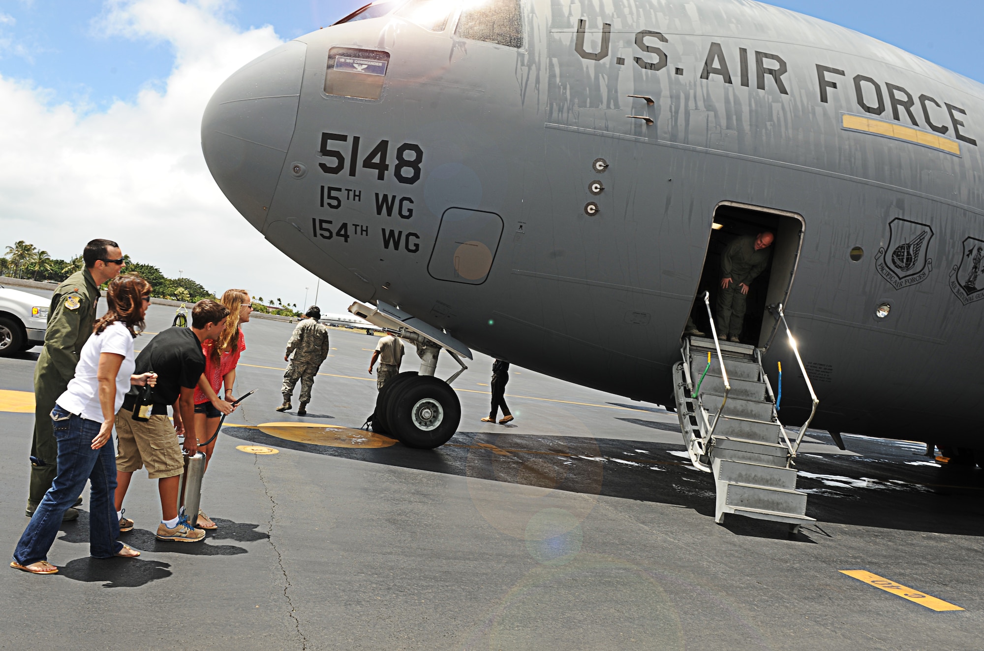 Col. Sam Barrett, 15th Wing commander, peeks around the corner, waiting to be hosed by his family after completing his fini-flight in a C-17 Globemaster III at Joint Base Pearl Harbor-Hickam, Hawaii, June 26. The flight was Barrett's last as the 15 WG commander. (U.S. Air Force photo/Senior Airman Lauren Main)