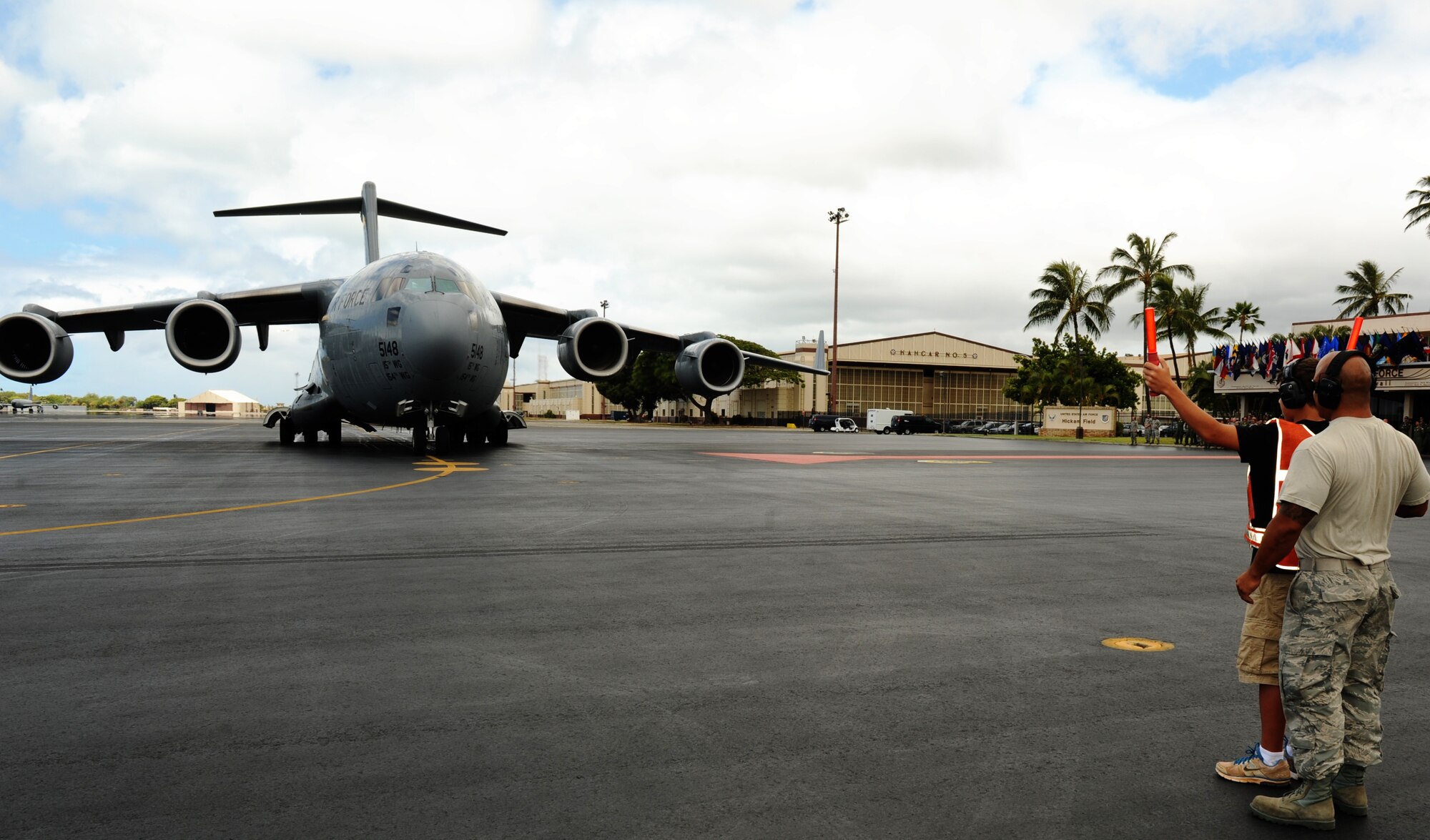 Sam Barrett Jr., son of Col. Sam Barrett, 15th Wing commander,  guides his father on to a parking space on the Hickam flightline at Joint Base Pearl Harbor-Hickam, Hawaii, June 26. Barrett had just completed his "fini-flight" and flown his last mission as the 15th WG commander. (U.S. Air Force photo/Senior Airman Lauren Main)