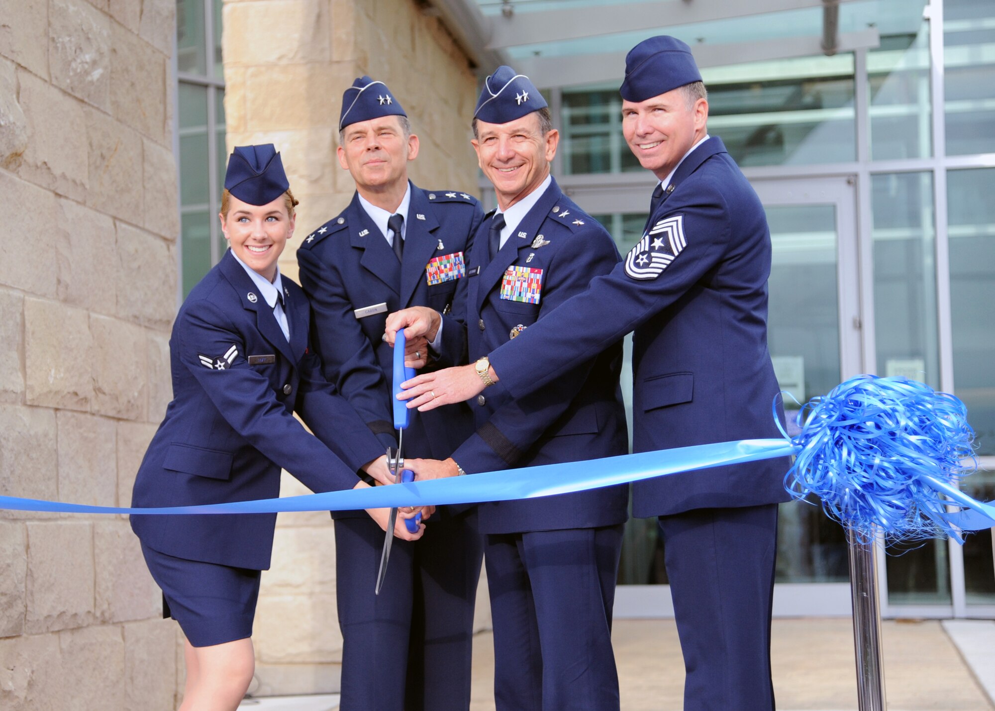 Airman 1st Class Chelsey Huff, Maj. Gens. Gerard Caron and Byron Hepburn and Chief Master Sgt. Richard Robinson (left to right) cut the ribbon in front of the new Air Force Postgraduate Dental School and Clinic at Joint Base San Antonio-Lackland, Texas, June 20. The school is the Air Force flagship for dental education and specialty services. Huff is a dental assistant for the 59th Dental Training Squadron and Caron is the assistant surgeon general for Dental Services and commander of the 79th Medical Wing. Hepburn is the director of the San Antonio Military Health System and commander of the 59th Medical Wing. Robinson recently retired as the command chief of the 59th Medical Wing. (U.S. Air Force photo/ Airman 1st Class Courtney Moses)