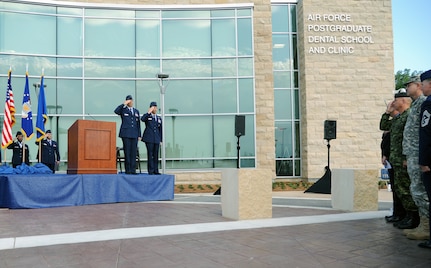 Maj. Gens. Byron Hepburn and Gerard Caron salute during the playing of the national anthem at the ribbon cutting ceremony for the new Air Force Postgraduate Dental School and Clinic, Joint Base San Antonio-Lackland, Texas, June 20. The school is the Air Force flagship for dental education and specialty services. Hepburn is the director of the San Antonio Military Health System and commander of the 59th Medical Wing. Caron is the assistant surgeon general for Dental Services and commander of the 79th Medical Wing. (U.S. Air Force photo/Airman 1st Class Courtney Moses)
