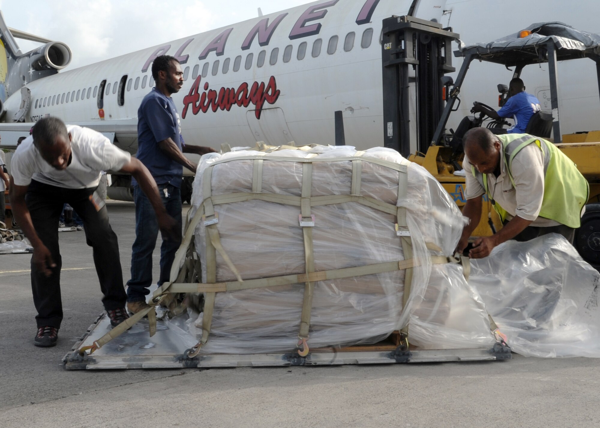 PORT-AU-PRINCE, Haiti – Haitian citizens unhook pallets of food and medical supplies on the Toussaint Louverture International Airport flightline, June 22, 2012. Fifty thousand pounds of food and medical supplies were delivered by an Altus Air Force Base aircrew to support the Mission Lifeline in Haiti, which cares for 11,000 men, women, and children. (U.S. Air Force photo by Airman 1st Class Franklin R. Ramos / 97th Air Mobility Wing / Released)