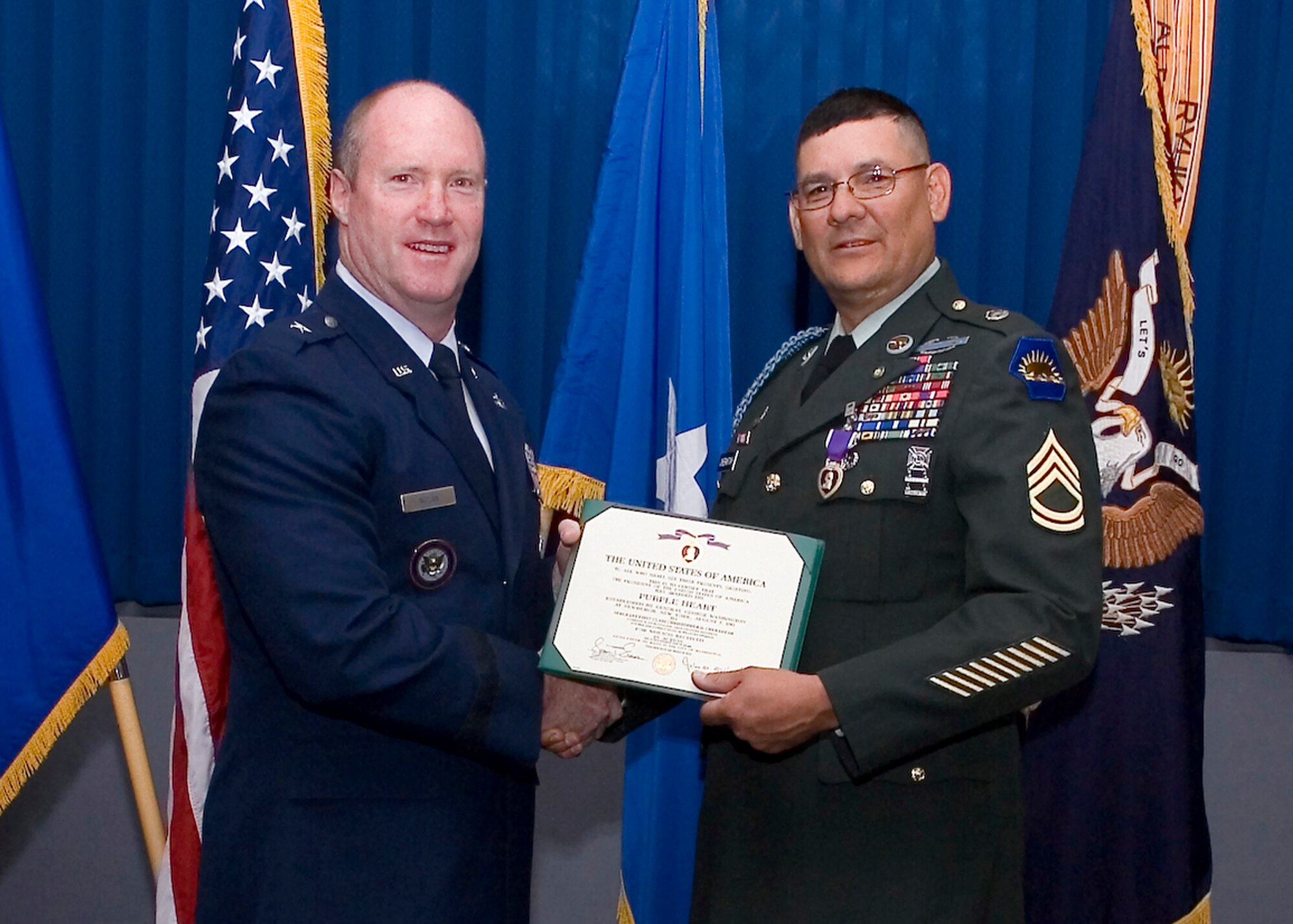 (Left) Brig. Gen. Robert C. Nolan II, former Air Force Flight Test Center commander, presents retired U.S. Army Sergeant First Class Chris Chebahtah with the Purple Heart June 18, 2012 in front of colleagues and family members. Chebahtah is currently an electrical technician with the 412th Maintenance Group Bomber Instrumentation shop who, while on a dismounted combat patrol with his squad on Dec. 14, 2005, was hit by an improvised explosive device resulting in his combat injuries. (U.S. Air Force photo by Jena Correa)