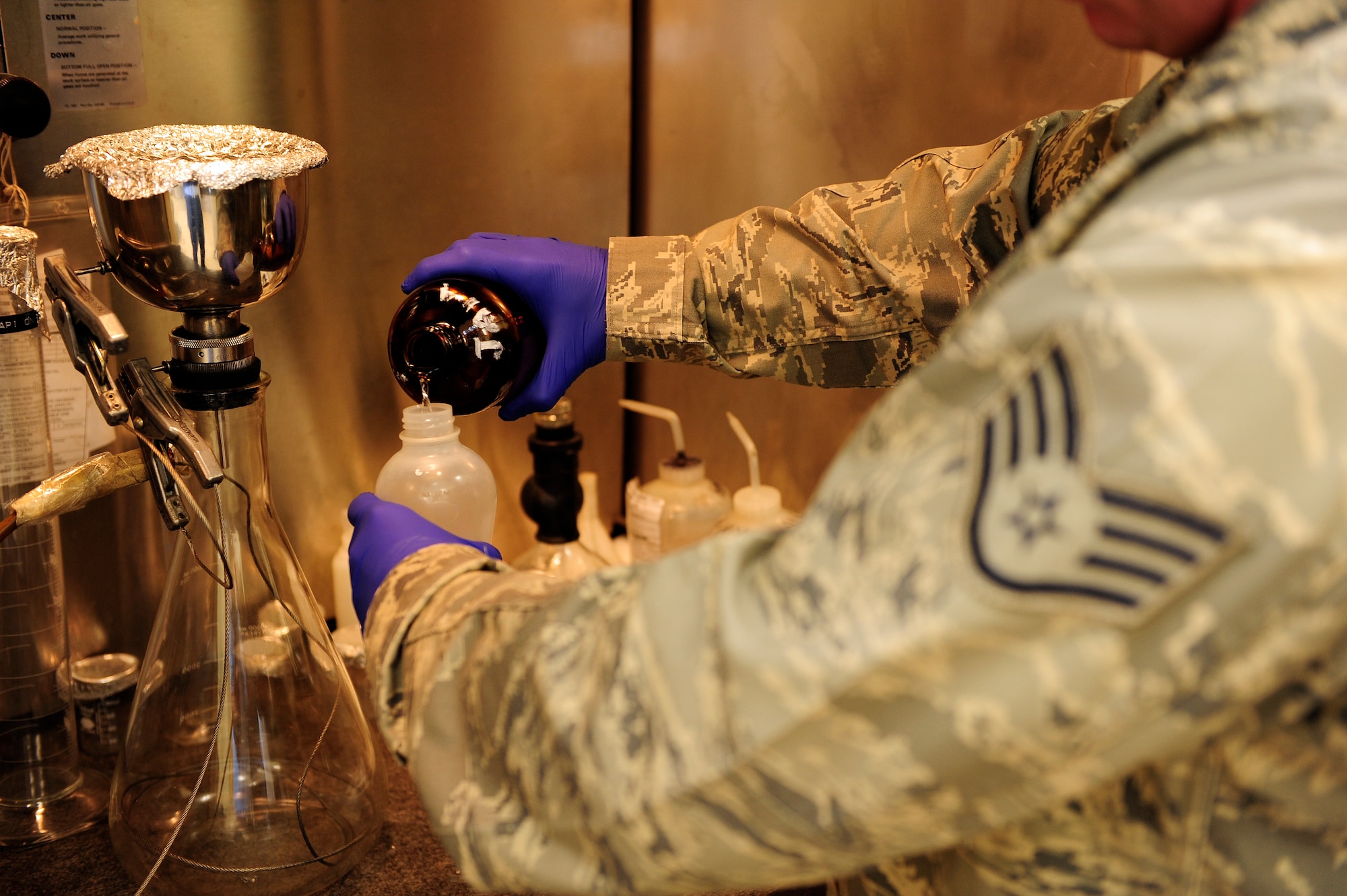 Staff Sgt. Jesse Ball, 20th Logistics Readiness Squadron fuels lab technician, carefully pours a fuel sample into a container for testing at Shaw Air Force Base, S.C., June 26, 2012. Quality assurance is necessary to verify that any fuel that goes into aircraft will yield maximum results and performance. (U.S. Air Force photo by Airman 1st Class Daniel Blackwell/Released)
