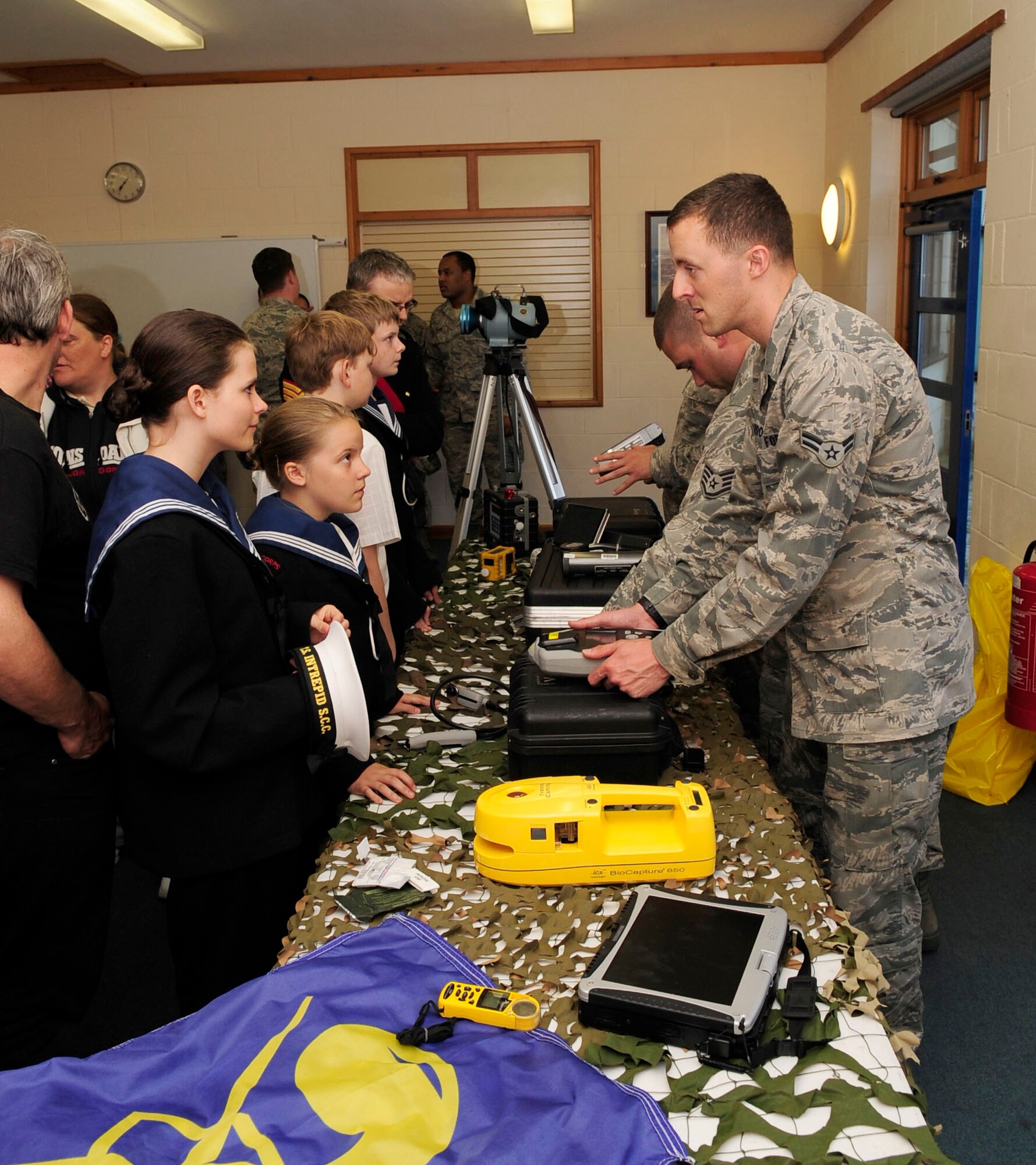 RED LODGE, England – Bettoney Kelsey, Sea Cadets Corps cadet, is shown chemical, biological, radiological and nuclear response equipment by Airman 1st Class Steven Carroll, 100th Civil Engineer Squadron Readiness Emergency Management Flight apprentice,  during the first Joint American-British Forces Appreciation Event held at the Millennium Center in Red Lodge June 22, 2012.The cadets were also allowed to try on CBRNE gear, view a military working dog demonstration and watch a U.S. Flag folding ceremony. (U.S. Air Force photo/Senior Airman Ethan Morgan)