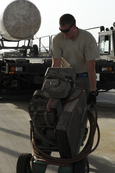Tech. Sgt. Mark Taylor, 380th Expeditionary Logistics Readiness Squadron Air Terminal Operations Center supervisor, hauls an air compressor unit out to a 60 kilo tunner loader June 26, 2012. Taylor is deployed to the 380th Air Expeditionary Wing from Joint Base Andrews, Md. (U.S. Air Force photo/Master Sgt. Scott MacKay) 

