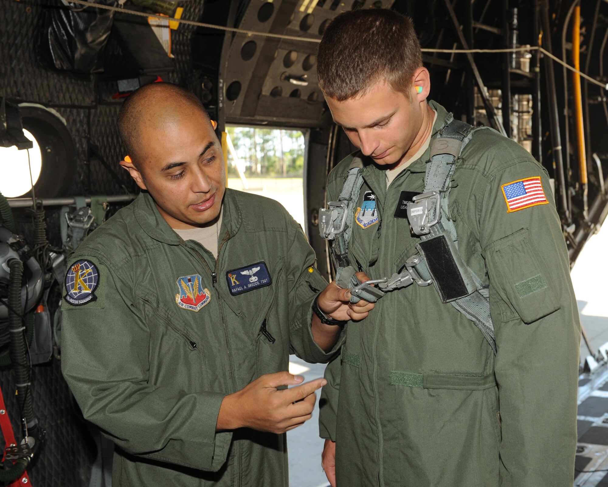 U.S. Air Force Tech. Sgt. Rafael Orozco, 71st Rescue Squadron, demonstrates how to put a safety harness buckle on U.S. Air Force Academy cadet Timothy Maciag at Moody Air Force Base, Ga., June 19, 2012. Cadets received an incentive flight as part of Operation Air Force, a program designed to introduce them to active duty life. (U.S. Air Force photo by Staff Sgt. Ciara Wymbs/Released)