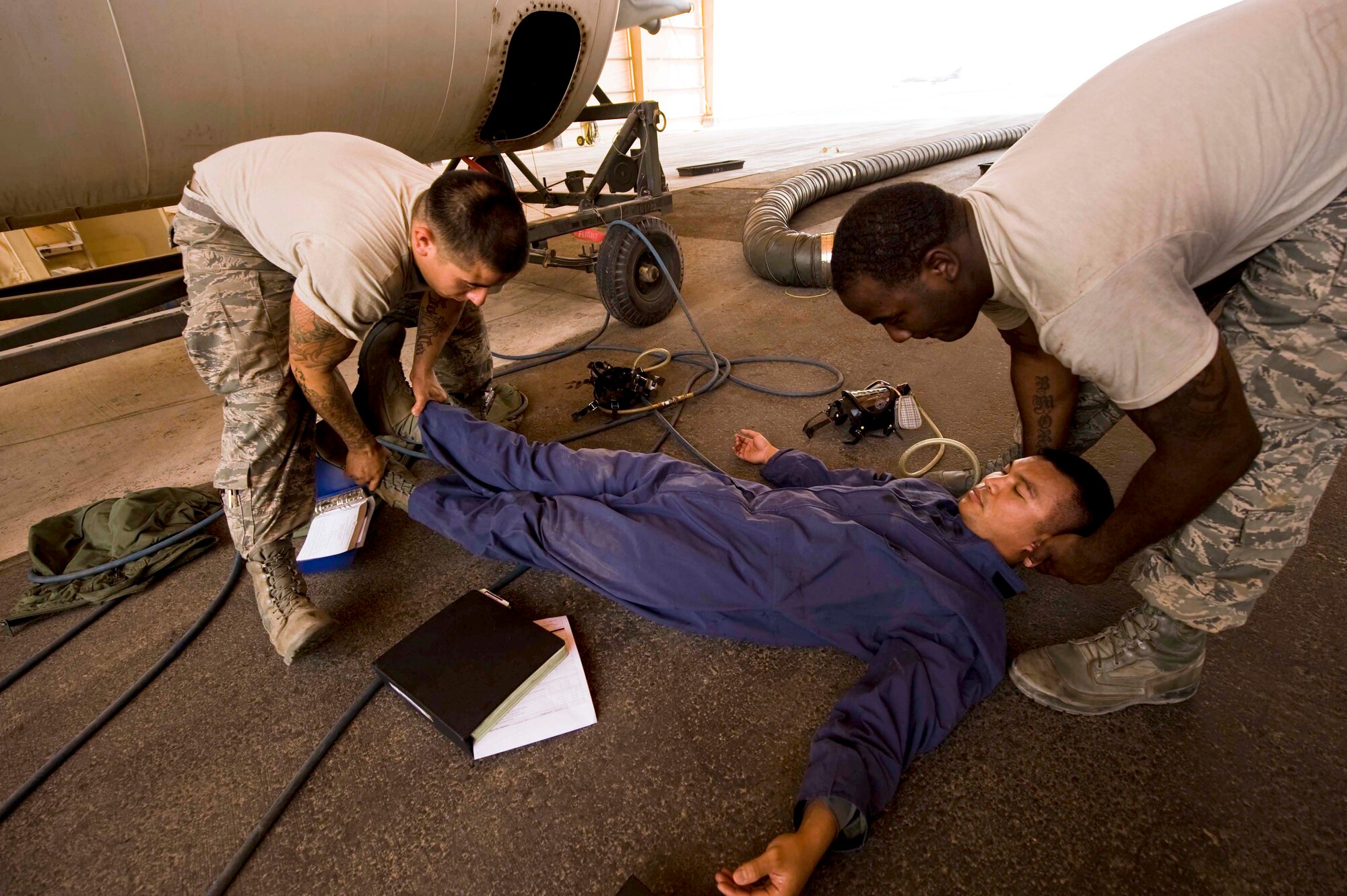 U.S. Air Force Senior Airman Robert Garcia (left) and Staff Sgt. Everett West (right) prepare to lift Senior Airman Ronald Lozada away from the B-1 Weapons bay tank after he was discovered non-responsive an annual confined space extraction exercise in Southwest Asia, June 19, 2012. All airmen are assigned to the 379th Expeditionary Maintenance Squadron. (U.S. Air Force photo/Staff Sgt. Sheila deVera)