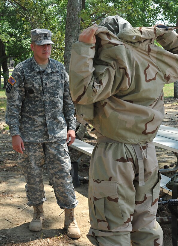 U.S. Army Staff Sgt. Cesar Ruiz, 47th Infantry Regiment, Drill Sergeant of the Year competitor, instructs Pvt. Ryan Max how to properly assemble and wear a chemical warfare suit, June 22, 2012, during the 2012 Drill Instructor of the Year Competition at Fort Eustis, Va. Ruiz is one of six competing for the 2012 award. (U.S. Air Force photo by Senior Airman Stephanie Rubi/Released)