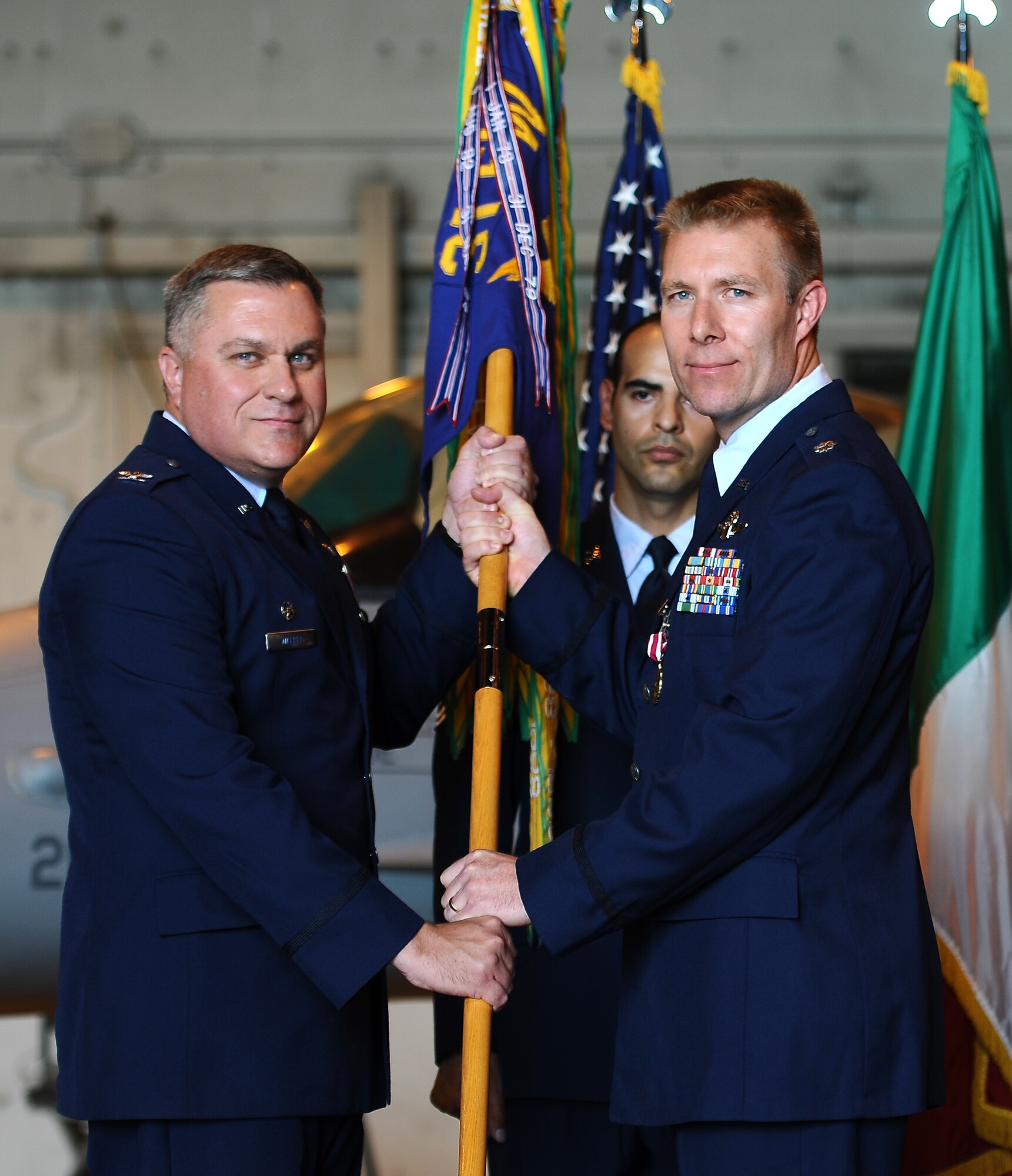 Lt. Col. Karl Ingeman, (right) former 555th Fighter Squadron commander, passes the squadron guidon to Col. David Walker, (left) 31st Operations Group commander, relinquishing command of the “Nickel.” Lt. Col. John Peterson, formerly Ingeman’s second in command, took up the reins during a ceremony June 25. (U.S. Air Force photo/Senior Airman Katherine Windish)
