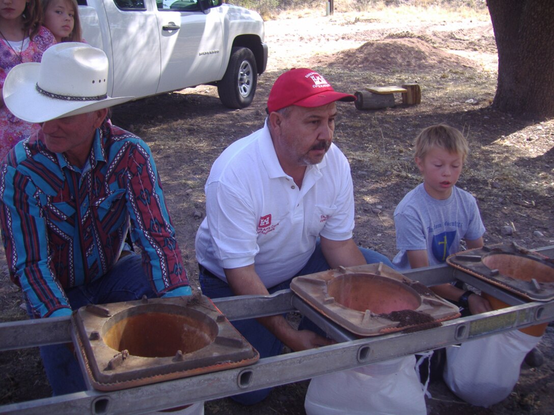 Catron county community members practice filling sandbags with the help of Corps employees.