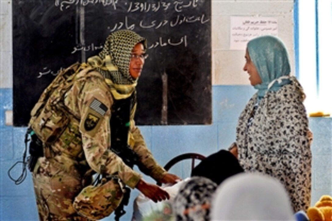 U.S. Navy Petty Officer 3rd Class Ryan Thomasallen, left, hands out toys during a visit to the orphanage in Farah City in Afghanistan's Farah province, June 19, 2012. 