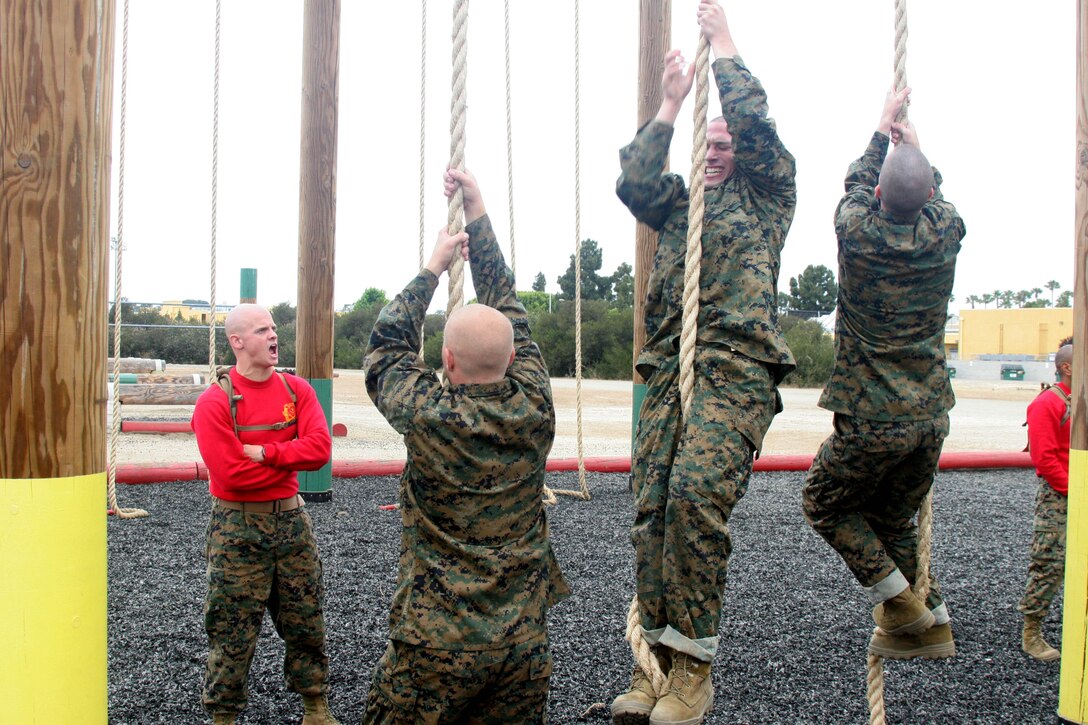 Sgt. William Getts, drill instructor, Company B, 1st Recruit Training Battalion, encourages recruits of Co. B to climb the ropes the correct way during the "O-course" June 15 aboard Marine Corps Recruit Depot San Diego. This "O-course" is a series of elevated bars, walls and logs that allow recruits to try different techniques to climb over as well as building upper-body strength.