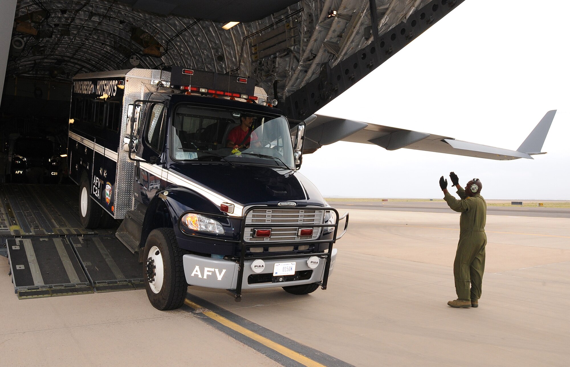 A C-17 loadmaster guides Hot Shot vehicles off the aircraft upon arrival at Peterson AFB, CO.  The Hot Shot firefighting crew is specially trained and equipped to prevent and suppress wildfires. They are the only specialized DoD wildland fire fighting team of their kind and are in Colorado Springs supporting Waldo Canyon Fire suppression efforts. (U.S. Air Force Photo/Duncan Wood)