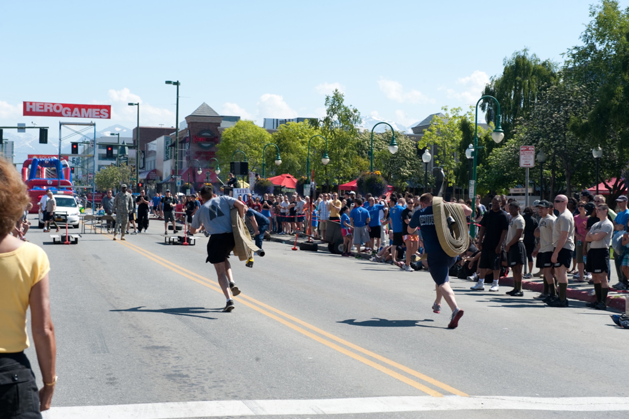 An Army member races against a member of the Anchorage Fire Department in an obstable course that involved events such as carrying a fire hose, completely changing a tire, eating a donut and whistling, and getting through an inflatable obstacle course during the Hero Games, part of the Solstice festival, in downtown Anchorage, Alaska June 23. Teams made up of Active Duty Army, Air Force, Guard, Reserve, the APD, fire department and other units participated in the friendly competition designed to improve morale and relations between the different units. On the longest day of the year-summer solstace-Anchorage, Alaska, gets 22 hours of functional daylight. (U.S. Air Force photo/Staff Sgt. Robert Barnett)