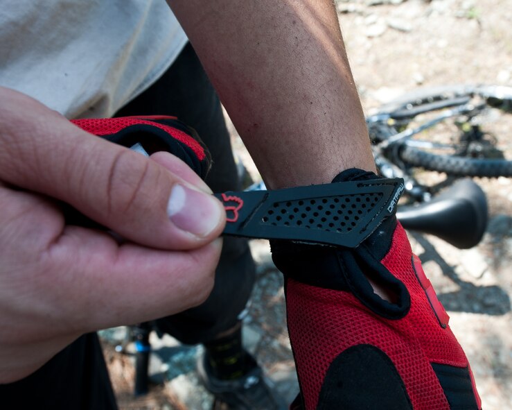Senior Airman Justin Faircloth, 28th Operations Support Squadron air traffic control technician, adjusts the straps on his biking gloves prior to starting a mountain biking trip at Storm Mountain, S.D., June 24, 2012. Biking gloves are used by cyclists to prevent blisters and cuts and also increase a biker’s grip allowing for more control. (U.S. Air Force photo by Airman 1st Class Alystria Maurer/Released)